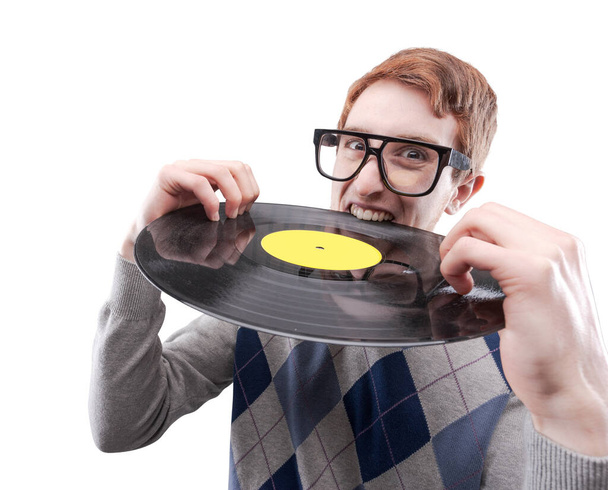 Funny nerd guy with big glasses, he is holding a vinyl record and biting it - Foto, afbeelding