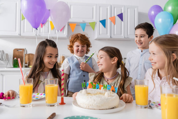 ομάδα χαρούμενων παιδιών γιορτάζει τα γενέθλια δίπλα σε νόστιμο κέικ κατά τη διάρκεια του πάρτι στο σπίτι - Φωτογραφία, εικόνα