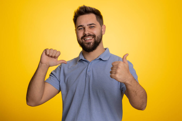 I am the best, choose me. Young excited caucasian man winner feeling very proud pointing hisself, looking self-confident, overjoyed by success. Handsome adult guy isolated on studio yellow background - Foto, Imagen