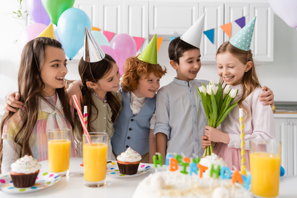 fröhliches Geburtstagskind mit Tulpen bei Freunden bei Feier zu Hause  - Foto, Bild