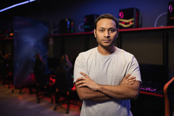 Indian gamer crossing arms and looking at camera in gaming club  - Fotó, kép