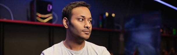 Indian man looking away while standing in gaming club, banner  - Фото, изображение