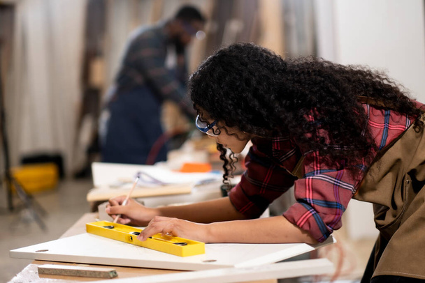 アフリカ系アメリカ人女性に焦点を当て家具工場で木材のピースに仕事をします,労働ハードワークの概念と休日や従業員のための休日. - 写真・画像