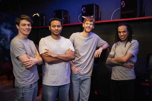 Cheerful interracial team crossing arms and looking at camera in gaming club  - Photo, Image