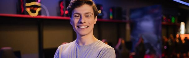 Portret pozytywnego młodzieńca patrzącego w kamerę w klubie gier, baner  - Zdjęcie, obraz
