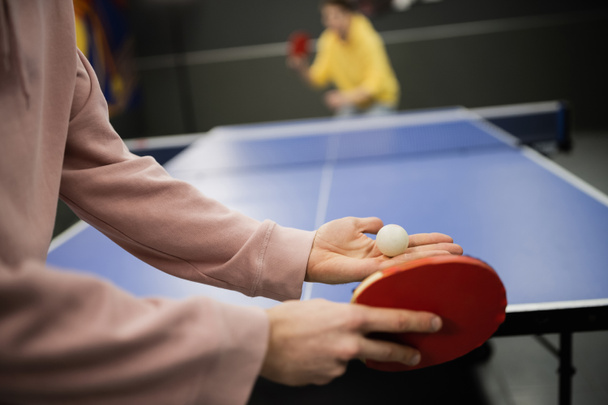 Gevoelig zicht op de man met racket en bal tijdens het spelen van tafeltennis in gaming club  - Foto, afbeelding