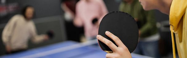 Cropped view of man playing table tennis with blurred friends in gaming club, banner  - Photo, Image