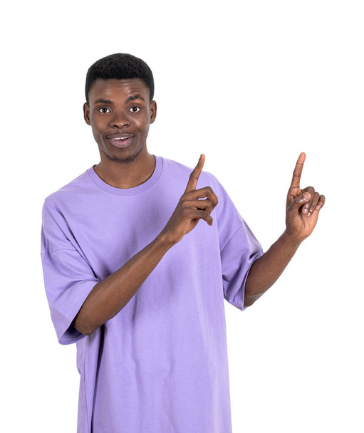 Smiling young black man in purple shirt, fingers pointing up. Isolated over white background. Concept of business offer and deal - Foto, Bild