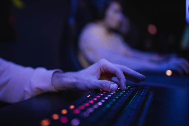 Cropped view of gamer using keyboard with lighting in cyber club  - Fotografie, Obrázek