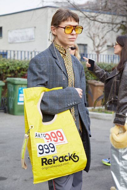MILAN, ITALY - FEBRUARY 24, 2023: Woman with yellow Repack bag, grey jacket and tie before Sportmax fashion show, Milan Fashion Week street style - Foto, afbeelding