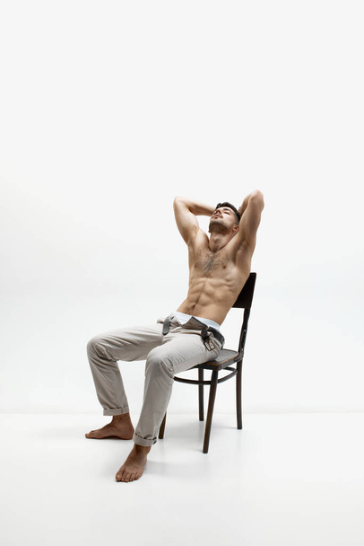 Naked torso, perfect body shape. Снимок красивого молодого мускулистого мужчины, позирующего без рубашки на белом фоне студии. Мужественность и сила. Концепция мужского здоровья, красоты мужского тела - Фото, изображение