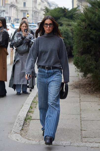 MILAN, ITALY - FEBRUARY 24, 2023: Woman with grey wool turtleneck and blue striped denim trousers before Philosophy by Lorenzo Serafini fashion show, Milan Fashion Week street style - Foto, immagini