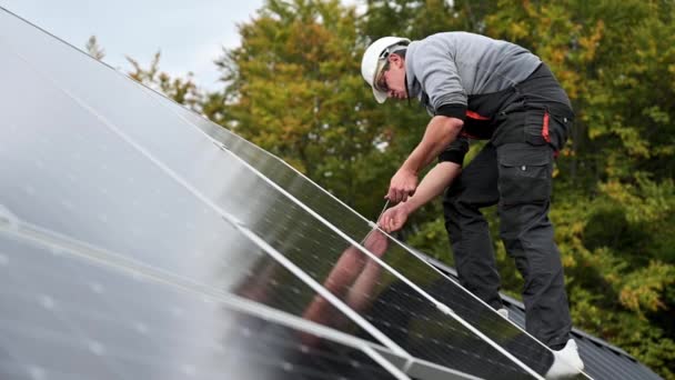 家の屋根の上に太陽光発電パネルをマウントする人技術者。六角キーの助けを借りて太陽電池モジュールシステムをインストールヘルメットのエンジニア。代替的再生可能エネルギーの概念. - 映像、動画