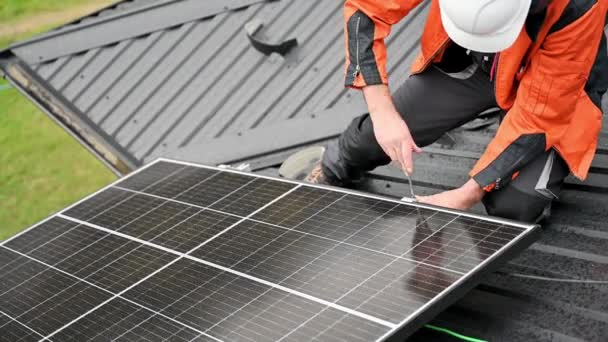 Evin çatısına fotovoltaik güneş panelleri monte eden teknisyen. Büyülü anahtarın yardımıyla güneş modülü sistemi kuran mühendisi kapatın. Alternatif, yenilenebilir enerji kavramı. - Video, Çekim