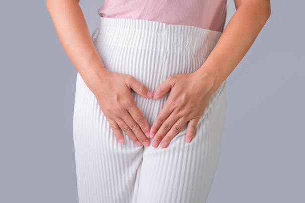 Woman with hands on her crotch isolated on white background. Female hand holding her crotch with pelvic pain or vaginal itching. gynecological problems. Health hygiene concept - Photo, Image