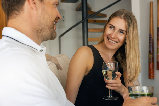 Gülümseyen genç çift evde buluşuyor ve şarap içiyor. - Fotoğraf, Görsel