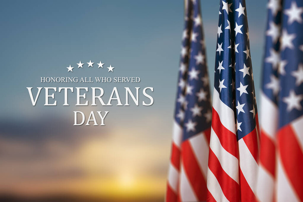 American flags with Text Veterans Day Honoring All Who Served on sunset background. American holiday banner. - Photo, Image