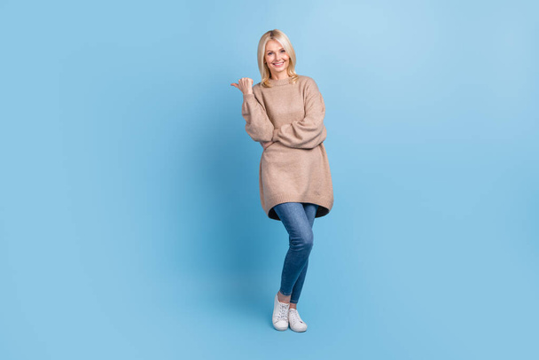Full body size photo of optimistic charming businesswoman wear beige sweater direct finger advert banner isolated on blue color background. - Fotó, kép