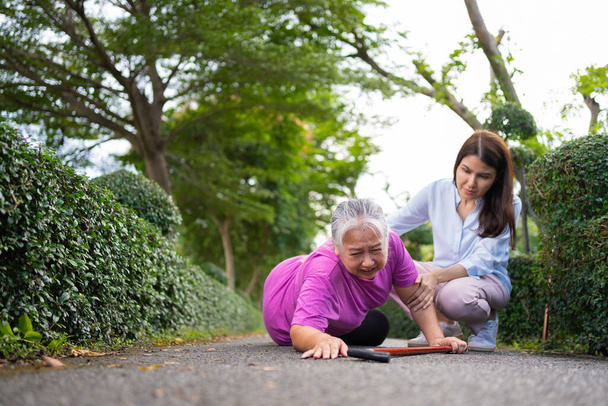 Asian senior woman fell down on lying floor because faint and limb weakness and Crying in pain form accident and her daughter came to help support. Concept of old elderly insurance and health care - 写真・画像
