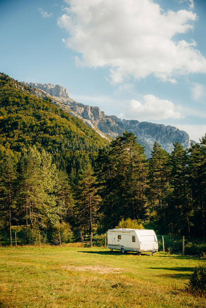 Caravan met een prachtig uitzicht op bos en bergen. Kampeervakantie en openlucht zomervakantie. Nomade levensstijl concept - Foto, afbeelding