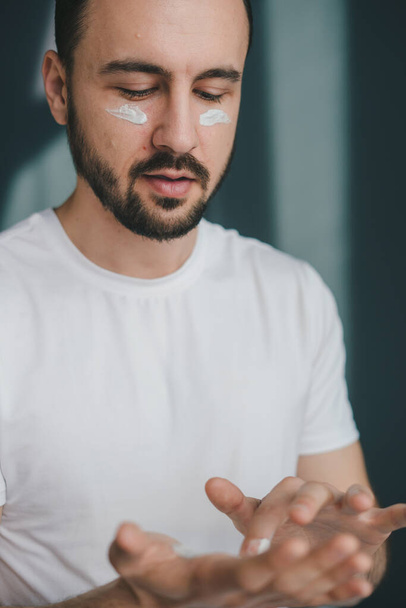 Closeup of handsome man using beauty products for his face, moisturising or nourishing skin at home. Facial skin care routine concept. Facial treatment - Foto, Imagen