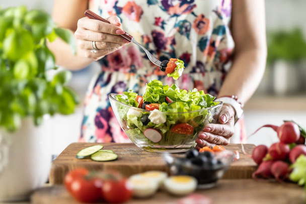A portion of healthy salad on a fork in the hand of a young woman. - Φωτογραφία, εικόνα