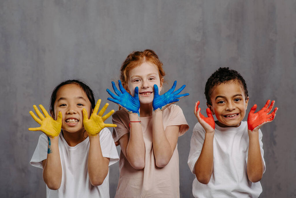 Portrait of happy kids with painted hands, studio shoot. - Foto, afbeelding