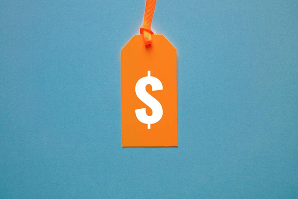 símbolo del dólar en etiqueta de precio naranja sobre fondo azul  - Foto, Imagen
