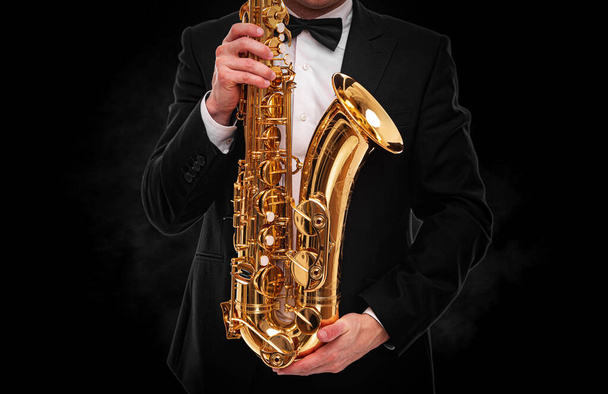 Saxophonist on a black background close-up. - Zdjęcie, obraz