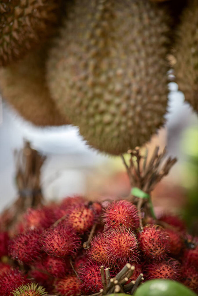 frutas tropicales, rambután rojo, durian y otros, en el mostrador de una tienda de carretera, enfoque selectivo - Foto, imagen