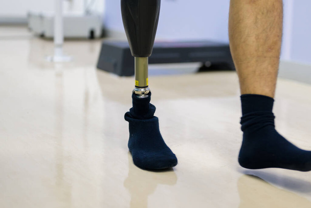 Protez bacağı olan genç bir protez teknisyen laboratuarda çalışıyor ve kalitesini kontrol ediyor. Protez üretiminde yüksek teknoloji mühendisi. - Fotoğraf, Görsel