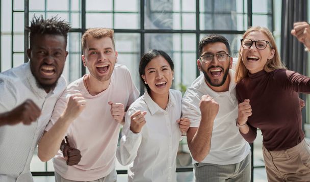Group of mono-ethnic corporate employees clenching their fists celebrating success - Foto, afbeelding