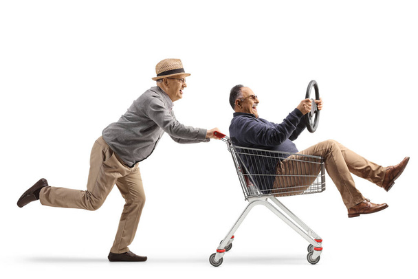 Idős férfiak szórakozás és lovaglás egy bevásárlókocsiban elszigetelt fehér háttér - Fotó, kép