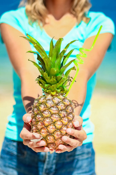 Pineapple in the hands of a man by the sea in nature on a journey background - Fotografie, Obrázek