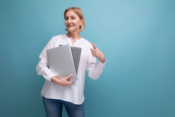 mulher adulta grave com cabelo loiro trabalhando remotamente usando laptop. - Foto, Imagem