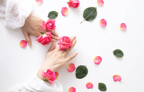 Όμορφα χέρια γυναίκα με τριαντάφυλλο λουλούδια είναι στο τραπέζι. Φυσικό καλλυντικό για περιποίηση δέρματος χεριών. Μακιγιάζ μόδας - Φωτογραφία, εικόνα