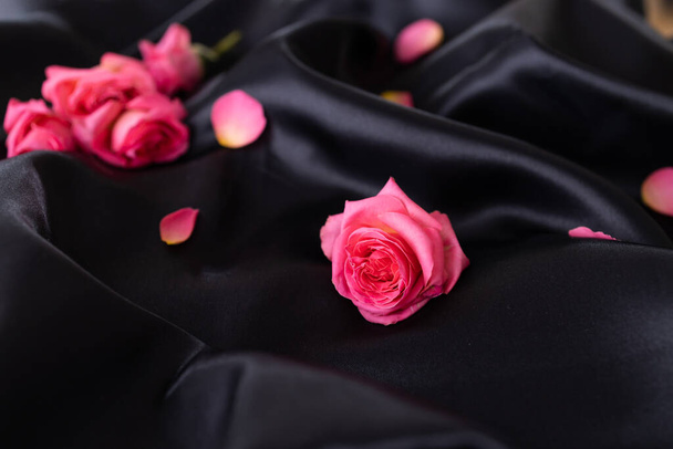 rosas rosadas sobre seda negra. rosas de color rosa claro en estilo suave y borroso para el fondo. - Foto, imagen