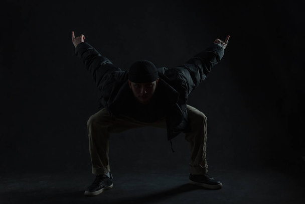 Μοντέρνος επαγγελματίας χορευτής με κομψά ρούχα που χορεύει στο σκοτάδι. Η σιλουέτα του χορού - Φωτογραφία, εικόνα