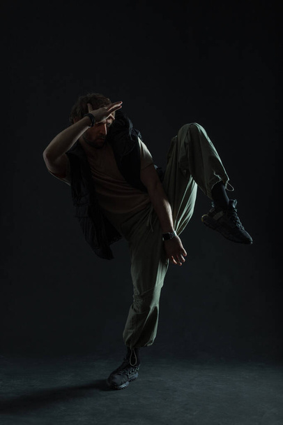 Silhouette of a dancing man in fashionable clothes on a black background in the dark - Photo, Image