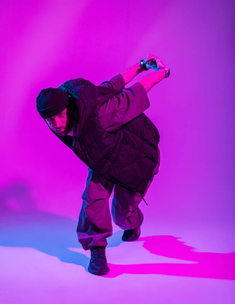Stylish dancer guy in trendy clothes dancing in a creative color studio with pink and neon lights - 写真・画像
