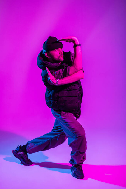 Fashionable young professional dancer man in fashion clothes dance in creative colorful studio with pink and neon light - 写真・画像