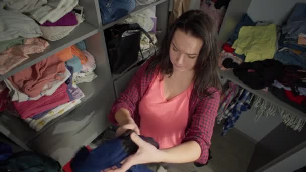 Egy nő kitakarítja a házat, és berakja a ruhákat a szekrénybe. Egy háziasszony dolgozik otthon. Kiváló minőségű 4k felvételek - Felvétel, videó