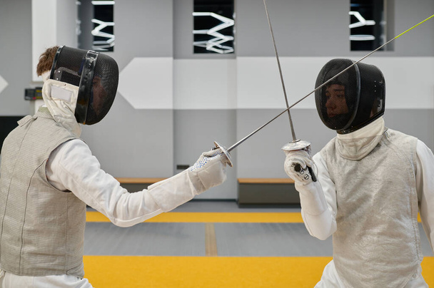Fechtpaar kämpft mit Degen und übt während des Unterrichts in der Kampfkunstschule Angriffs- und Verteidigungskombination - Foto, Bild