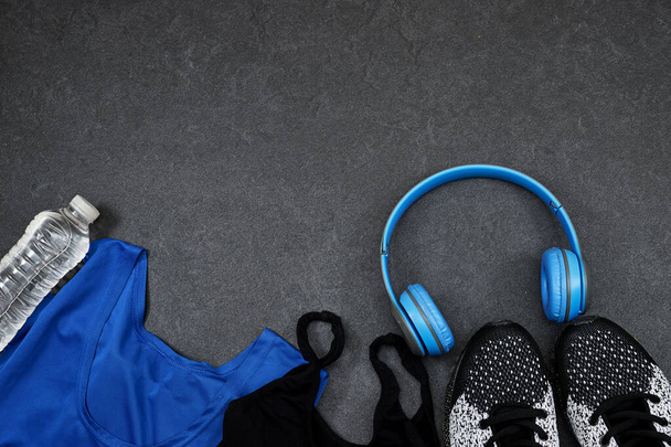 Terveellinen elämäntapa, urheilu tai urheilijan laitteet setti: mies tai nainen vaatteet ja pullo vettä sininen langaton kuuloke ja lenkkarit harmaalla pohjalla - Valokuva, kuva