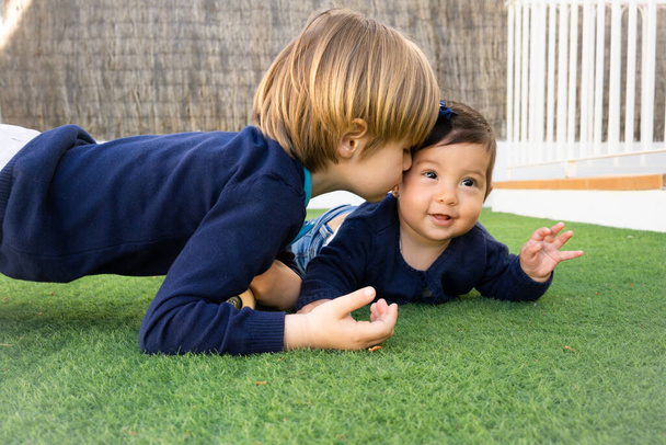 Photo de frère et soeur s'amusant dans le parc, deux enfants joyeux allongés sur l'herbe verte, petite fille et garçon jouant à l'extérieur, meilleurs amis, famille heureuse, amour et bonheur concept - Photo, image