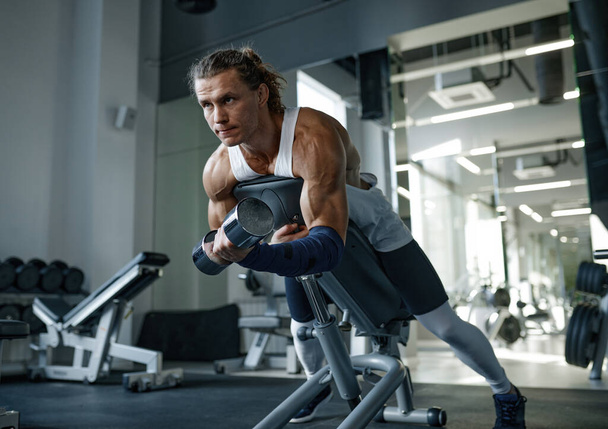 Hezký silný muž zvedání činky na fitness lavičce tréninkové svaly v tělocvičně. Kulturistika cvičení a posilování koncepce cvičení - Fotografie, Obrázek