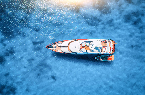 Літом у блакитному морі на заході сонця видніється прекрасна розкішна яхта і човен. Острів Сардинія, Італія. Верхній вигляд швидкісного човна, морського узбережжя, прозорої води. Подорож. Тропічний ландшафт. Яхтинг - Фото, зображення