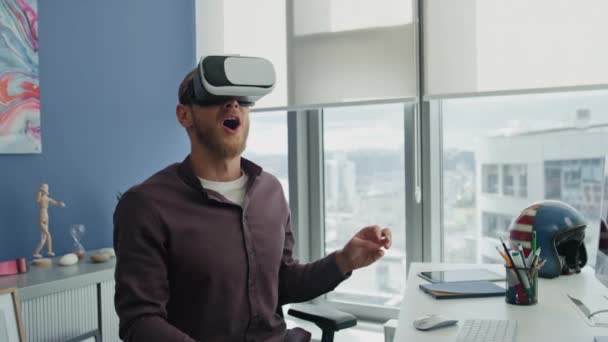 Surprised millennial experiencing vr in hipster office closeup. Impressed man exploring metaverse world at remote workplace. Excited programmer enjoying new immersive simulation game at modern home  - Footage, Video