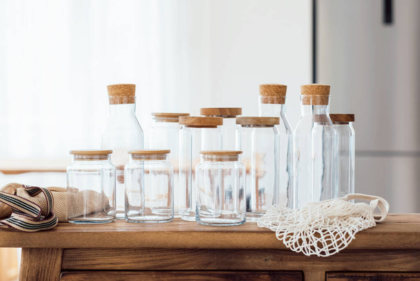 Zero waste concept. Textile eco-bags, empty glass jars on a wooden table in the kitchen. Eco-friendly reuse concept. Selective focus.  - Fotoğraf, Görsel