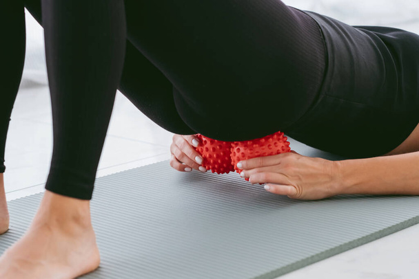 背中の痛みを排除するために小さなボールに横たわっ女性,硬い筋肉や腰痛をマッサージ,仙骨や背骨の痛みを緩和するための演習を実行します.筋肉の弛緩と伸張 - 写真・画像